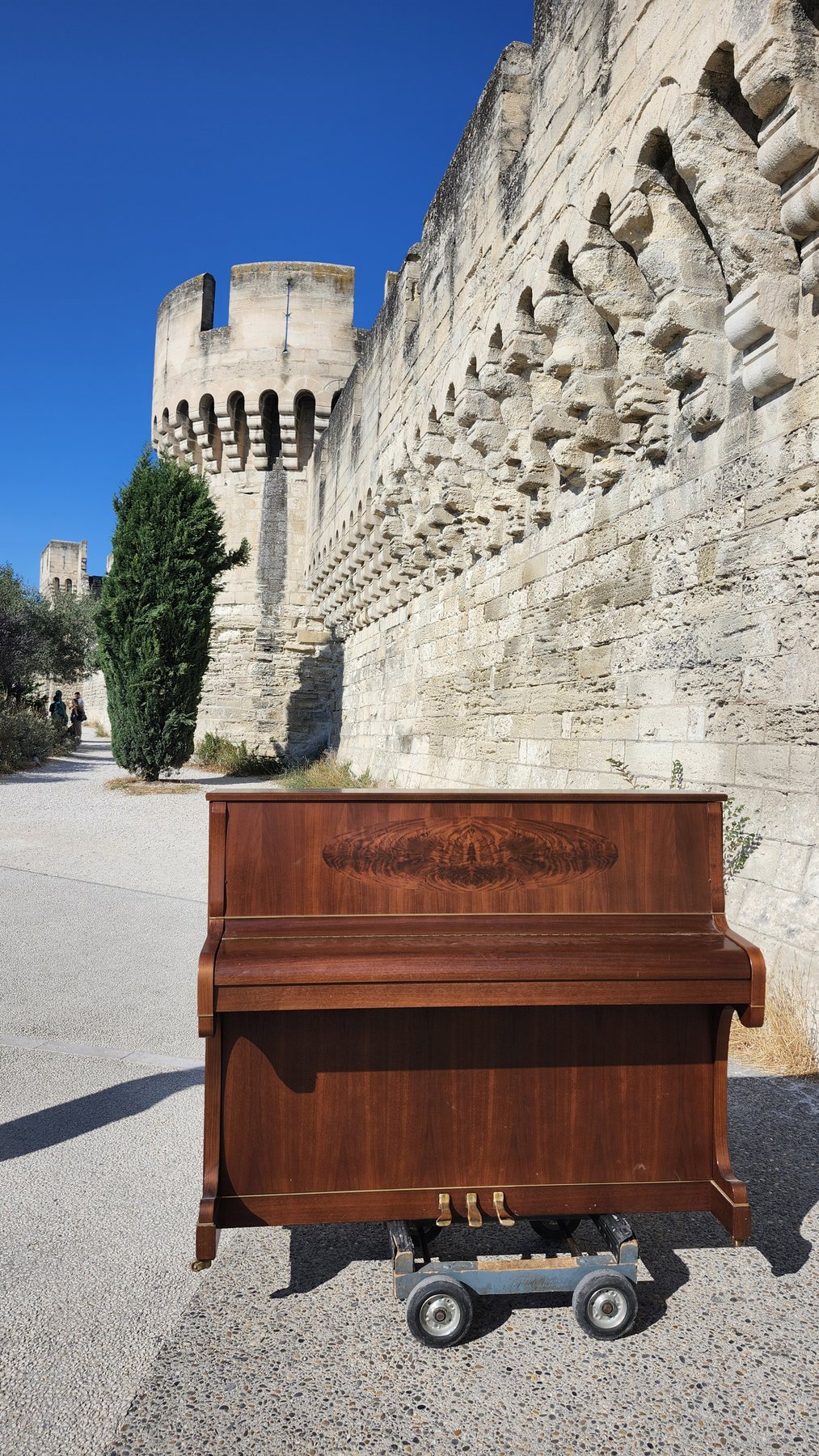 Piano droit sur son chariot devant un monument en pierre